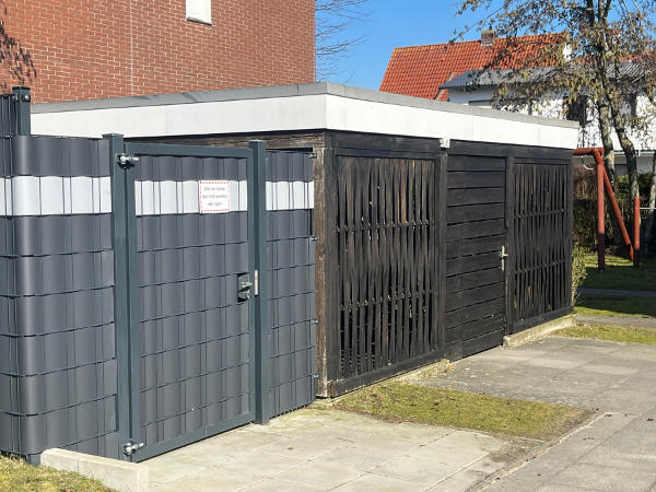 Abschließbare Fahrradgarage und links davon Abfallsammelstelle